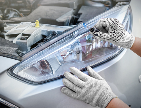 Hands in gloves with lamps near car headlights